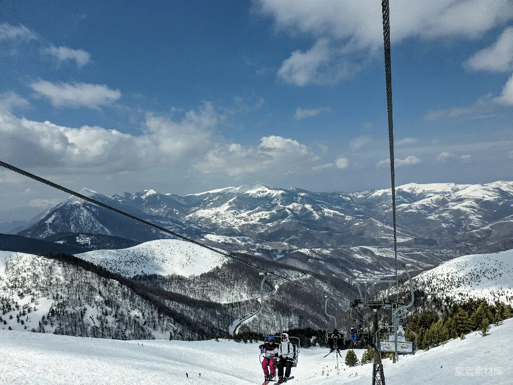 高清摄影  山顶上白天人们乘坐雪橇在覆雪的山间滑雪。