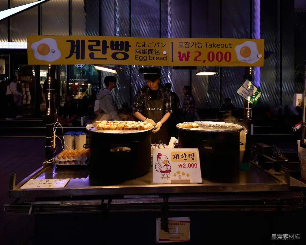 高清摄影 一个男人站在桌上堆满食物的前面。