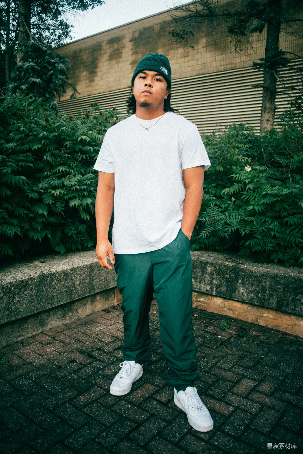 高清摄影  白色连帽T恤和黑色长裤的男人在白天站在绿色植物附近近处站立。