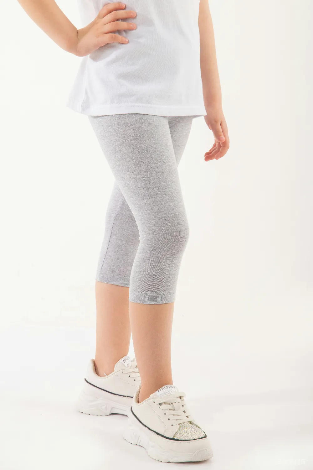高清摄影  一个穿着白色上衣和灰色 leggings 的小女孩