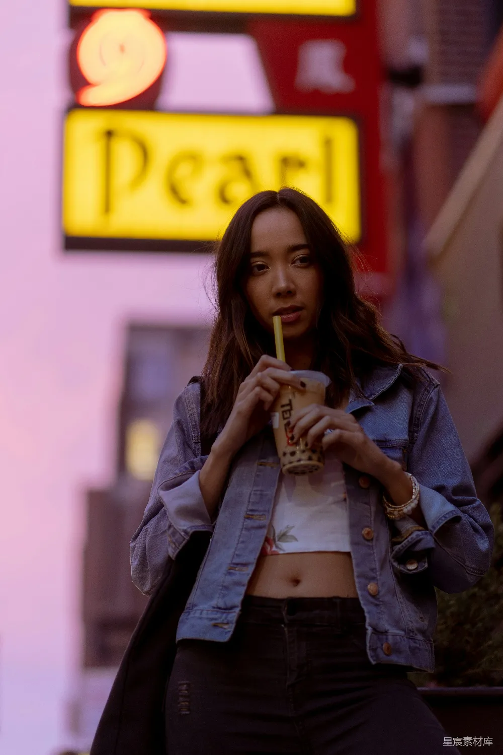高清摄影  一位妇女站在霓虹灯前，手中拿着一杯酒。