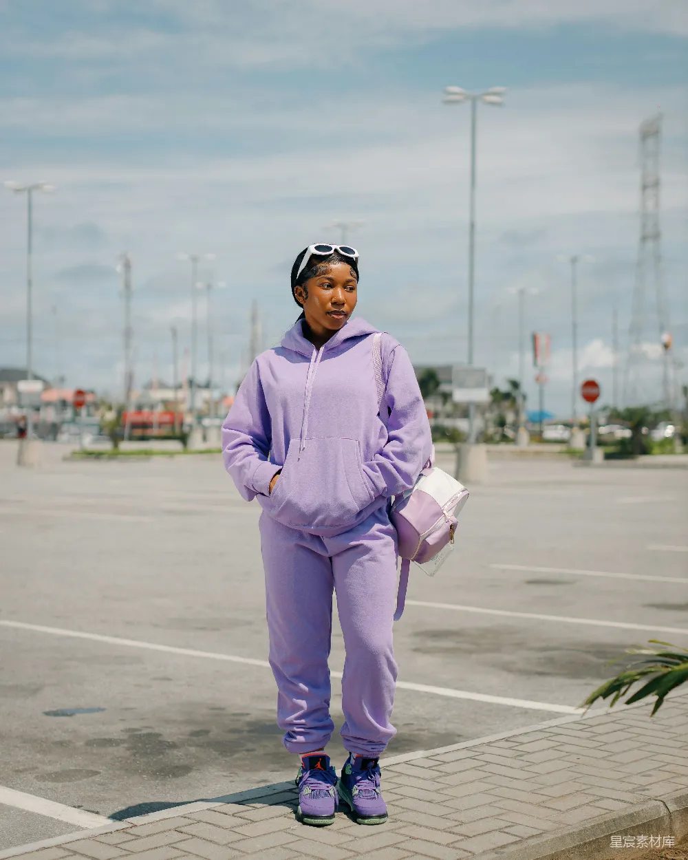 高清摄影 一个穿着紫色衣服的女人站在停车场里。