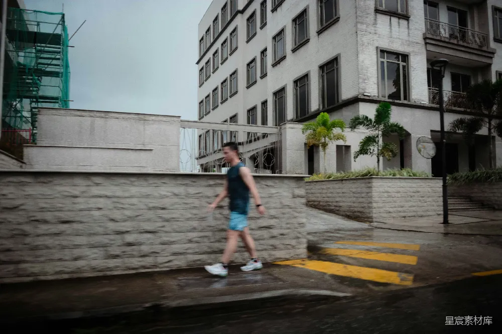 高清摄影  一个男人走在一栋高楼上边的街道上
