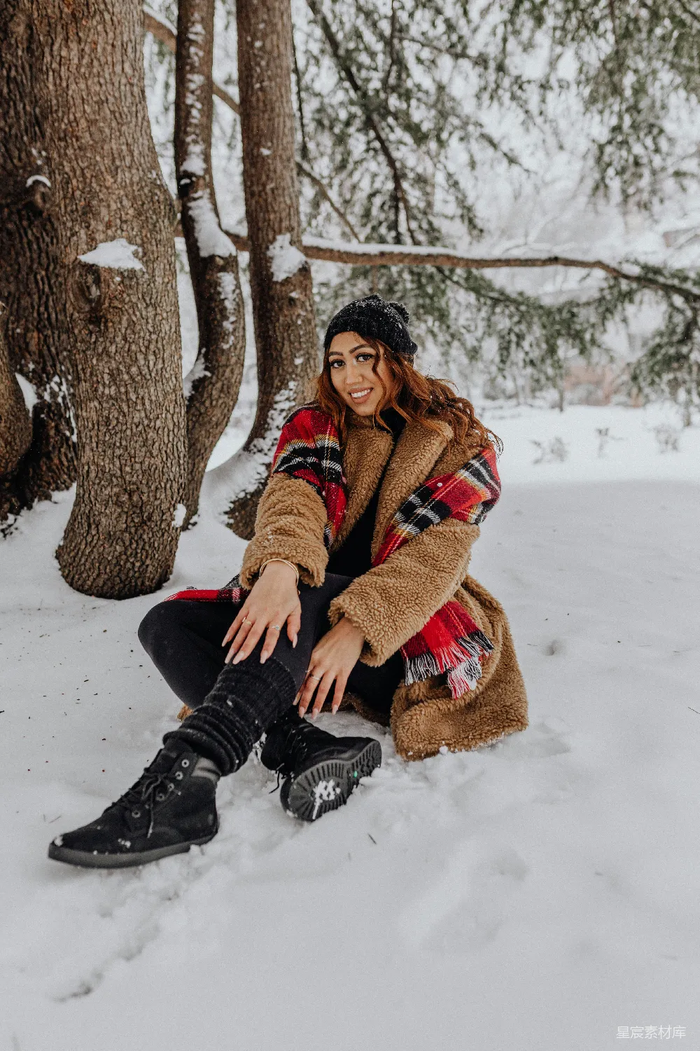 高清摄影  一个妇女坐在雪中穿着靴子。