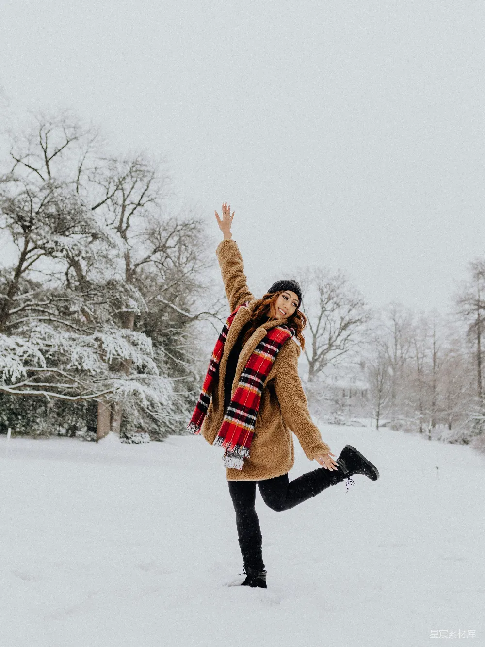 高清摄影  一个女人站在雪地里，双臂高高举起。