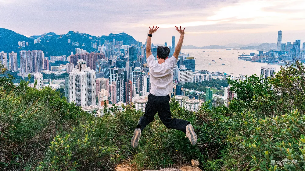 高清摄影  男人举手向空中跳，俯瞰城市 skyline。
