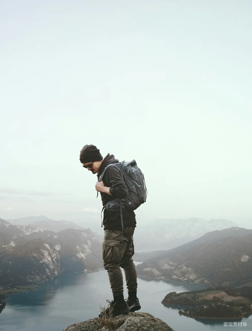 高清摄影  一个男人站在岩石上，俯瞰一片水域。