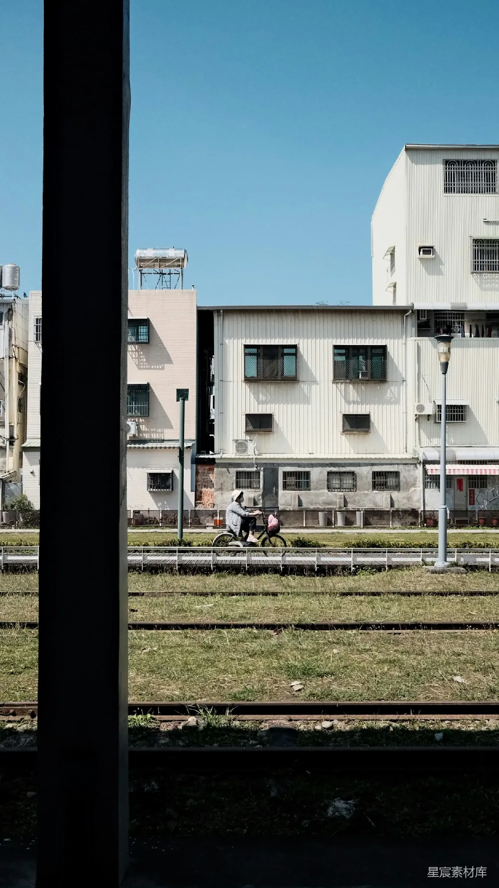 高清摄影  人们骑车经过建筑和铁轨。