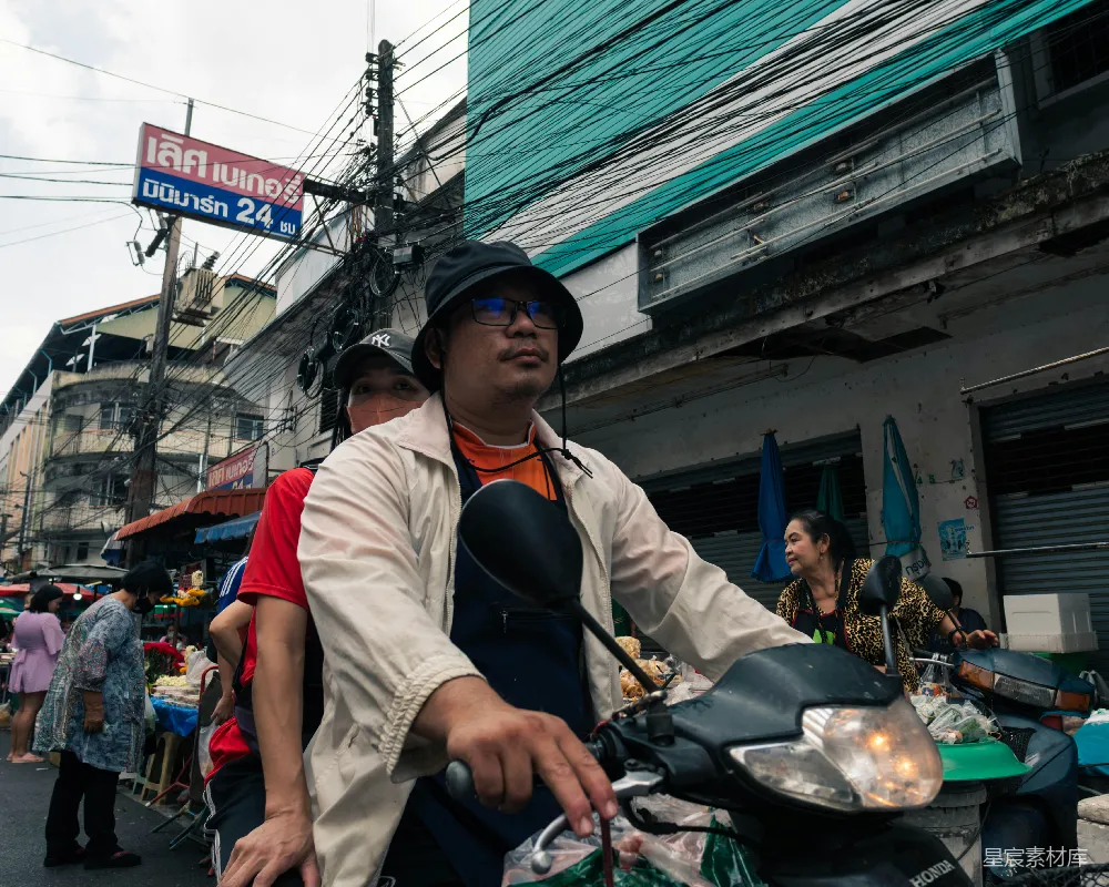 高清摄影  一个男人骑在摩托车后座上沿着街道前行。