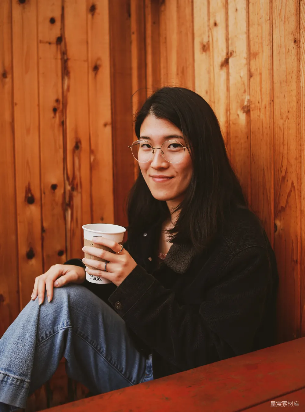 高清摄影 人物 一个女人坐在长椅上，手中拿着一杯咖啡。