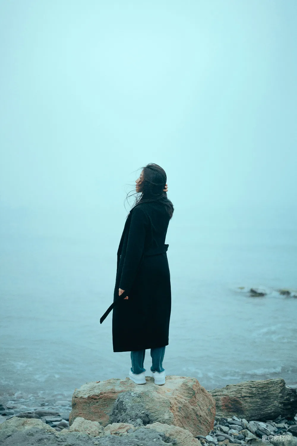 高清摄影  一个女人站在岩石上，望着大海。
