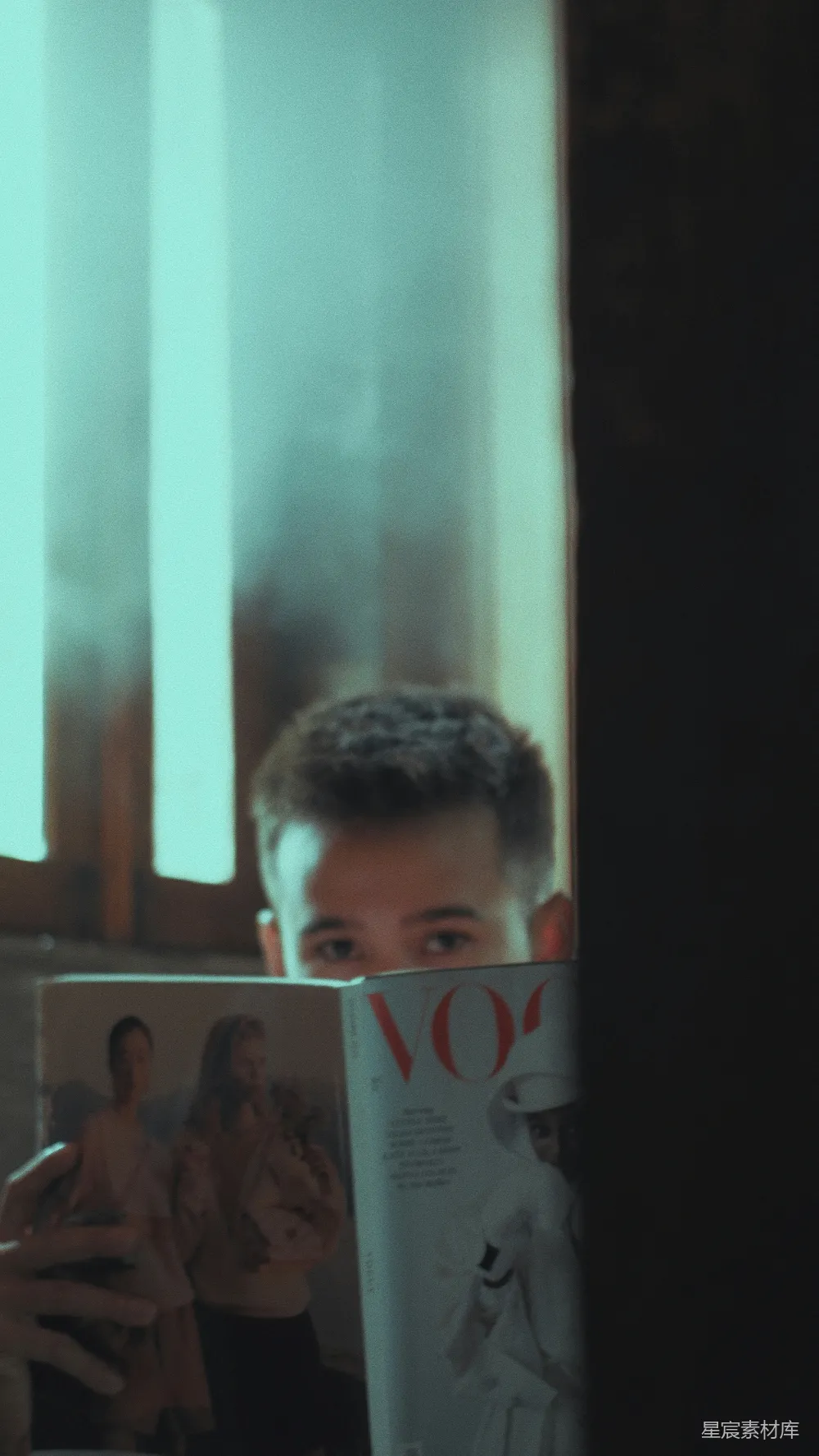 高清摄影 一个男人在窗前阅读杂志。