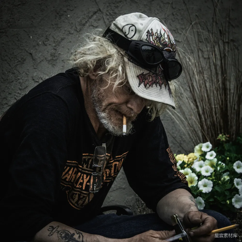 高清摄影 黑色T恤上衣的男人戴着黑色墨镜和白色帽子，手持智能手机。