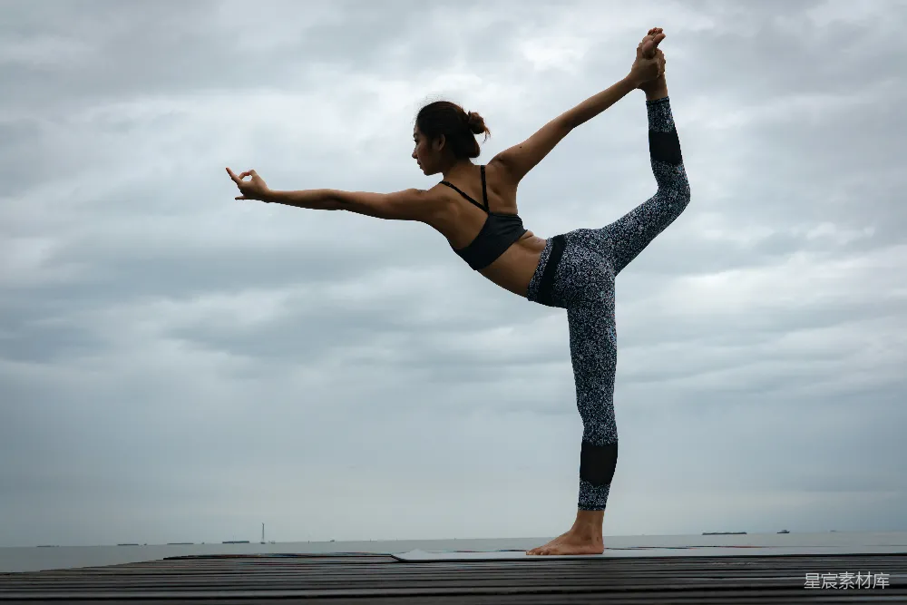 高清摄影  黑色紧身胸衣和蓝色运动 leggings 的女性在白天进行瑜伽练习。