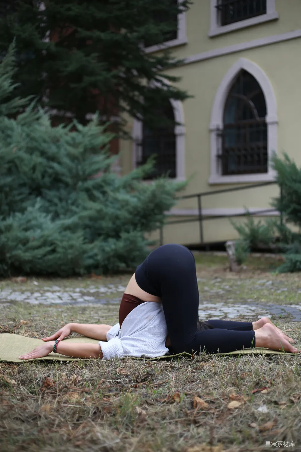 高清摄影  一个女人躺在瑜伽垫前的建筑物前