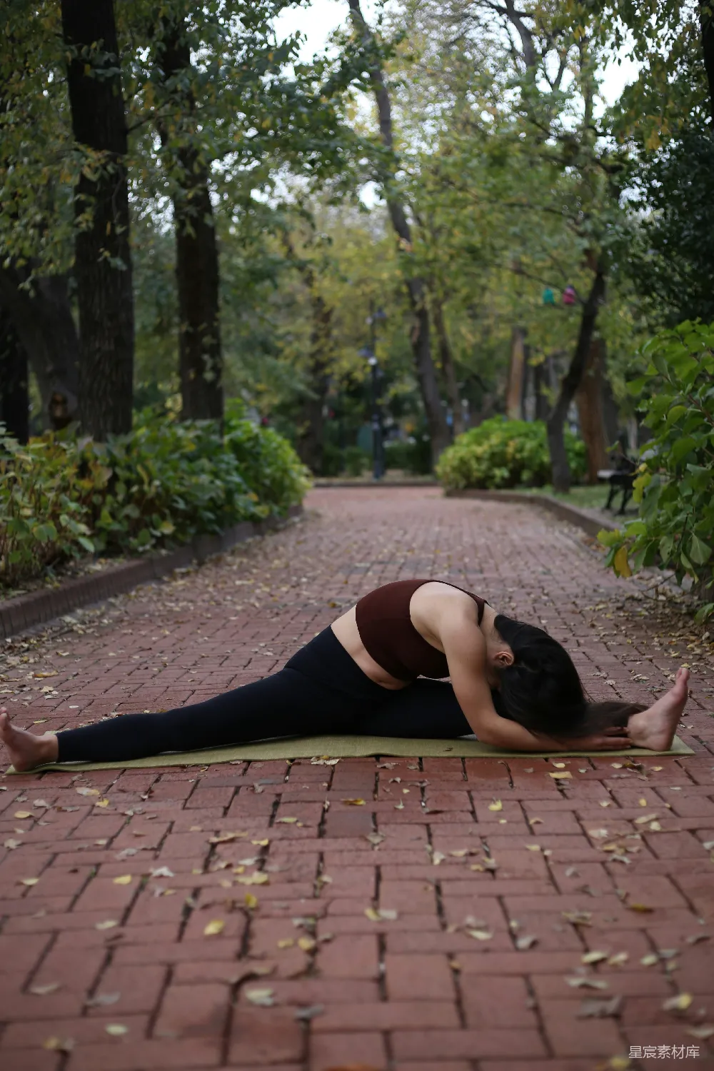高清摄影  一位女性正在砖砌小径上做瑜伽姿势。
