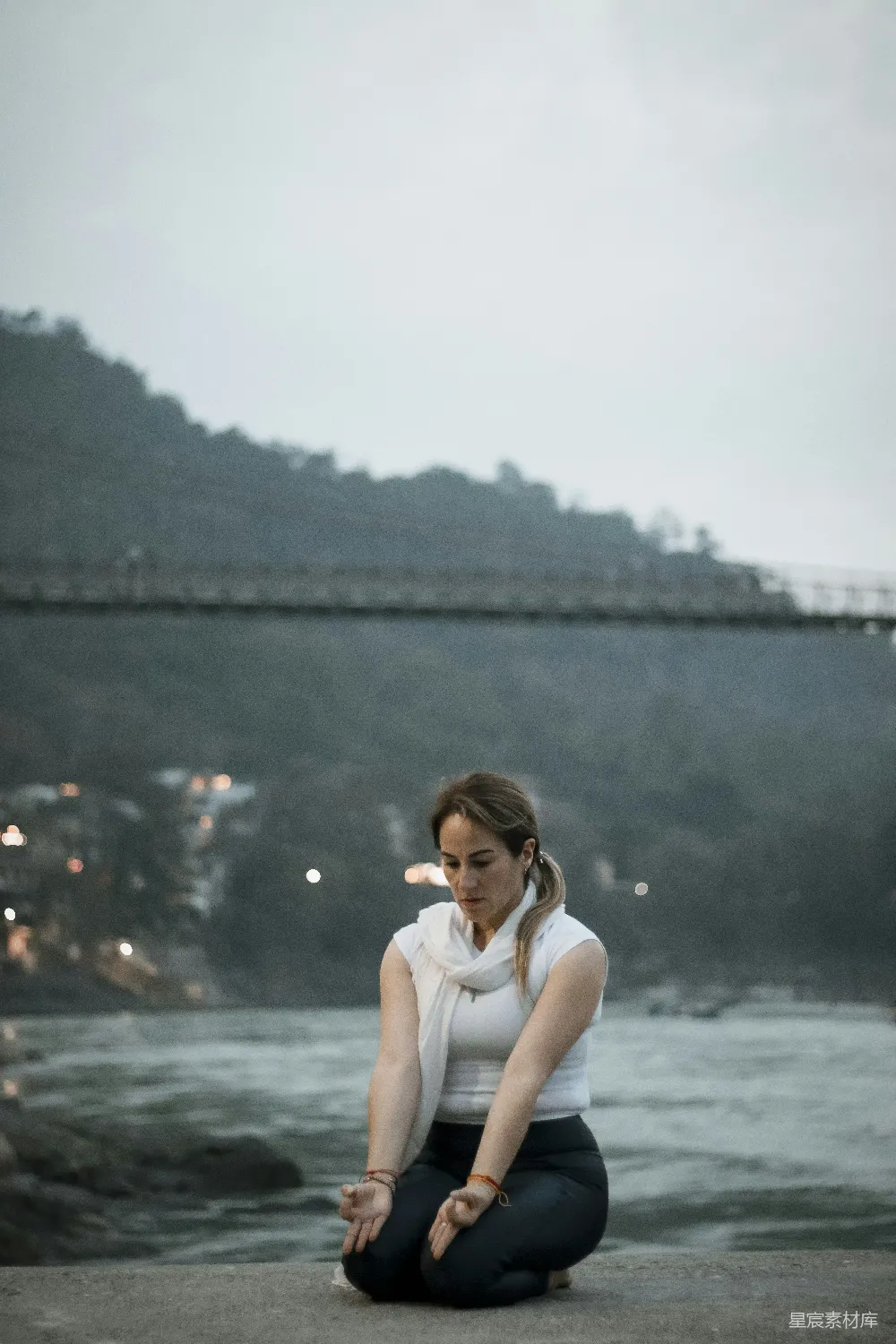 高清摄影 地上坐着一位妇女，面前是一条河。