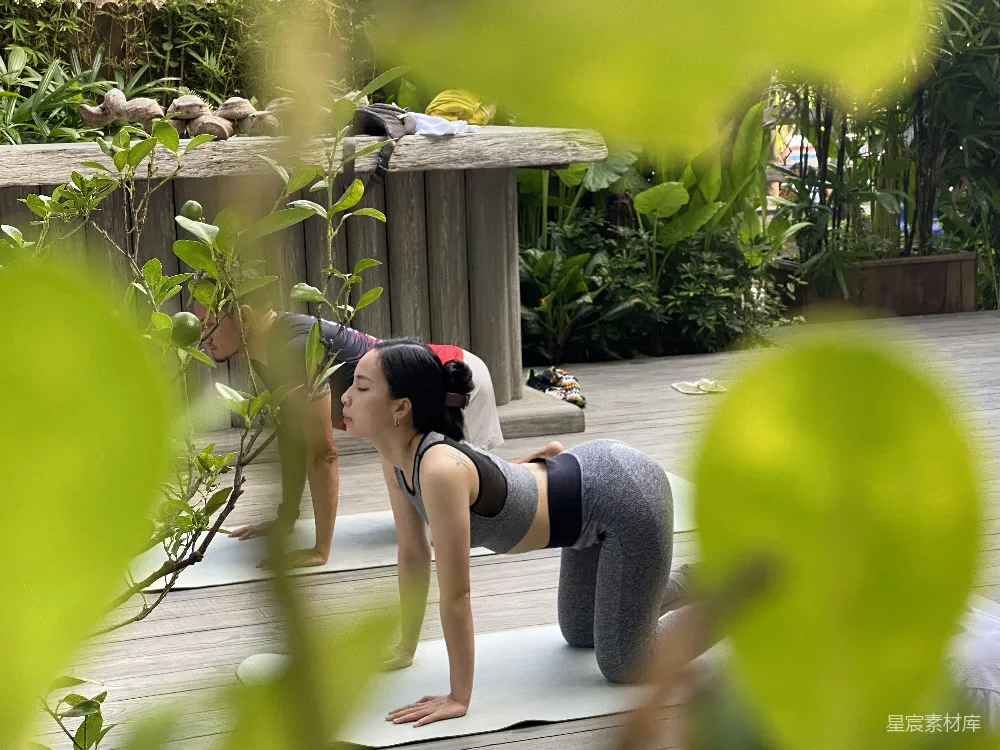 高清摄影  一位女性正站在瑜伽垫上做着一个瑜伽姿势。