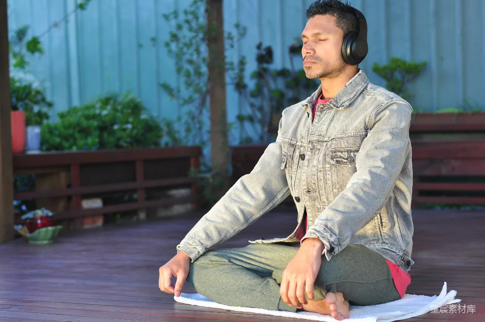 高清摄影 一个男人坐在桌子上，戴着耳机。