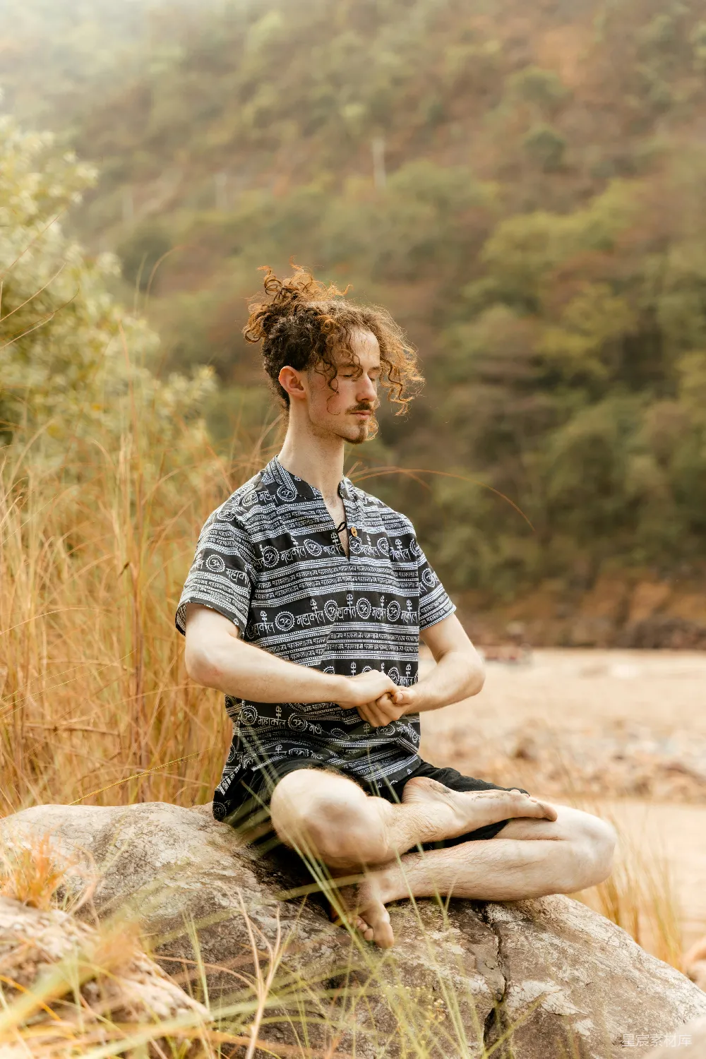 高清摄影  一个男人坐在岩石上做瑜伽