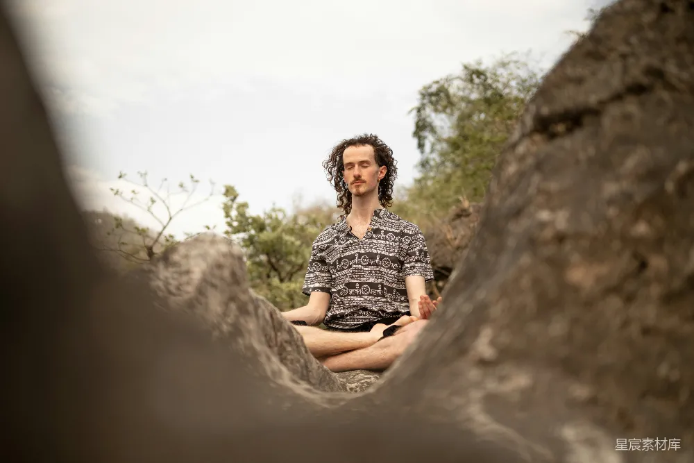 高清摄影 一个男人坐在森林中央的一块岩石上