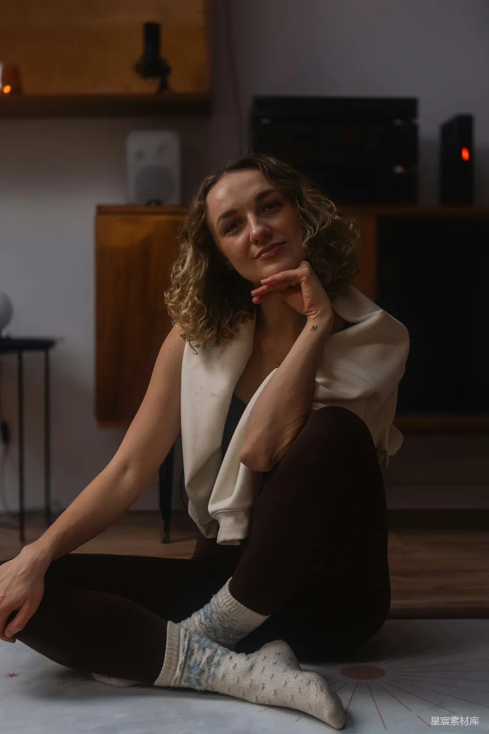 高清摄影 一头 curly 发的年轻女子坐在地板上。