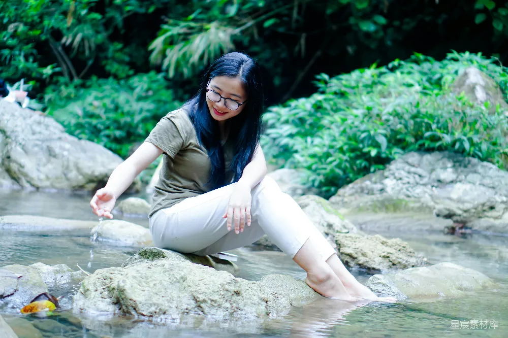 高清摄影  一个女人坐在水边的岩石上