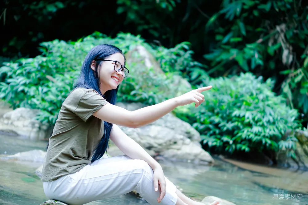 高清摄影 一位女性坐在岩石上，正指着某物。