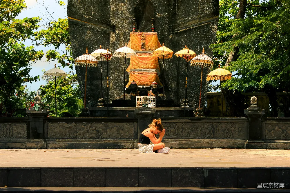 高清摄影 妇女坐在古石 altar 前，有伞。