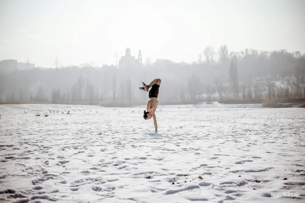 高清摄影 黑色上衣和棕色短裤的女人在雪地上白天跳跃，地面覆盖着积雪。