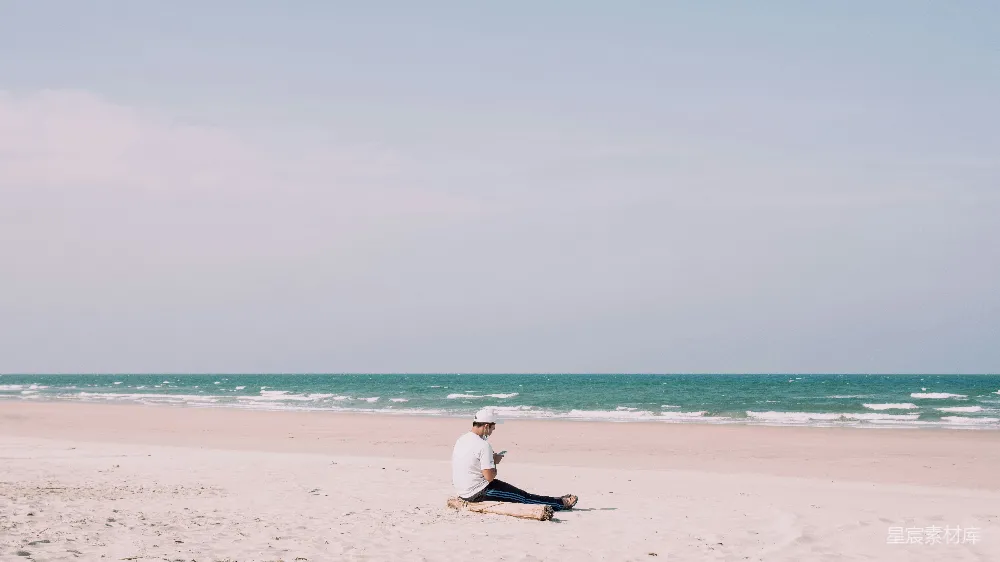 高清摄影 一个男人坐在海边，旁边是海洋。