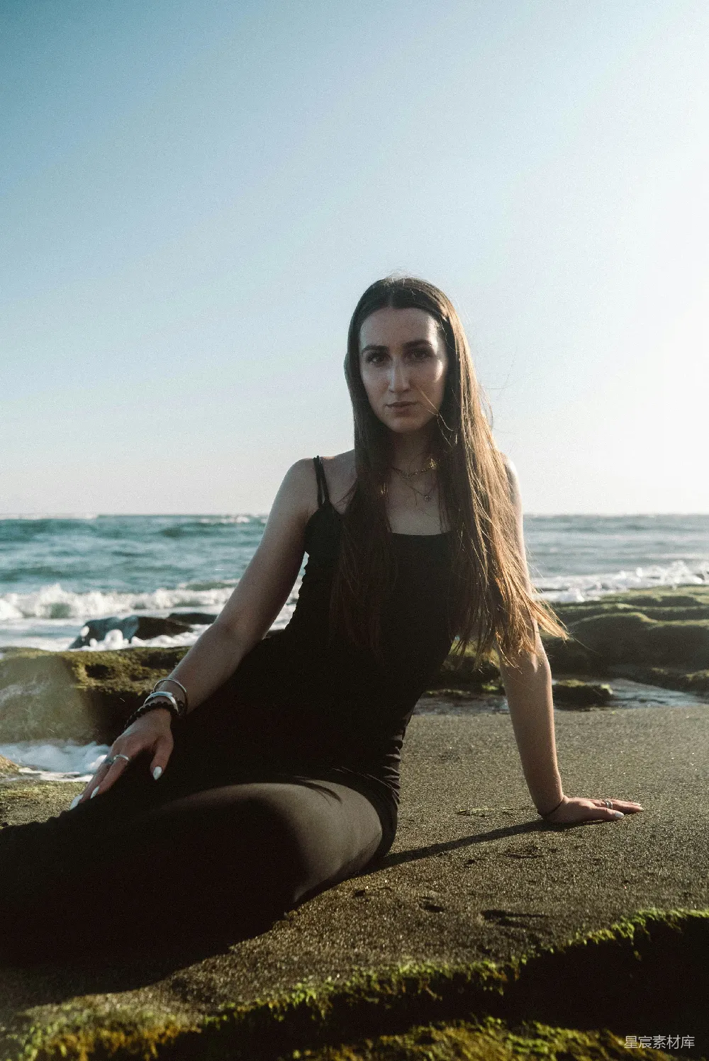 高清摄影 海滩上坐着一位女性，双腿交缠。