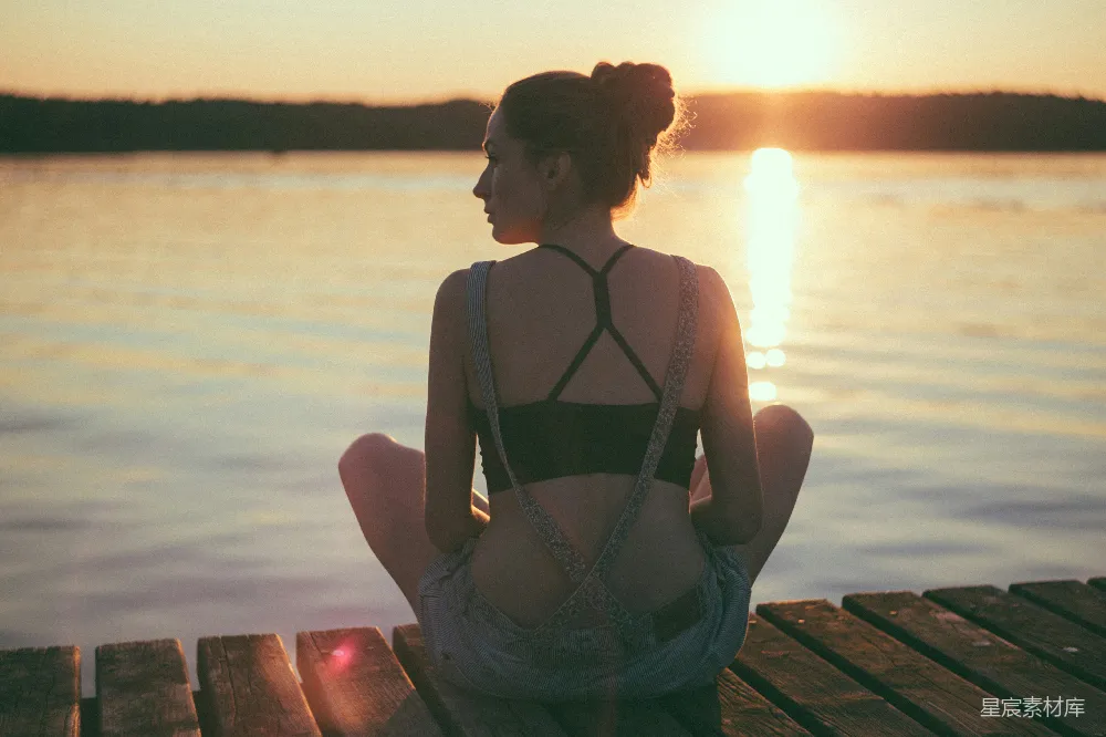 高清摄影 女人坐在棕色木制的码头上，夕阳西下。