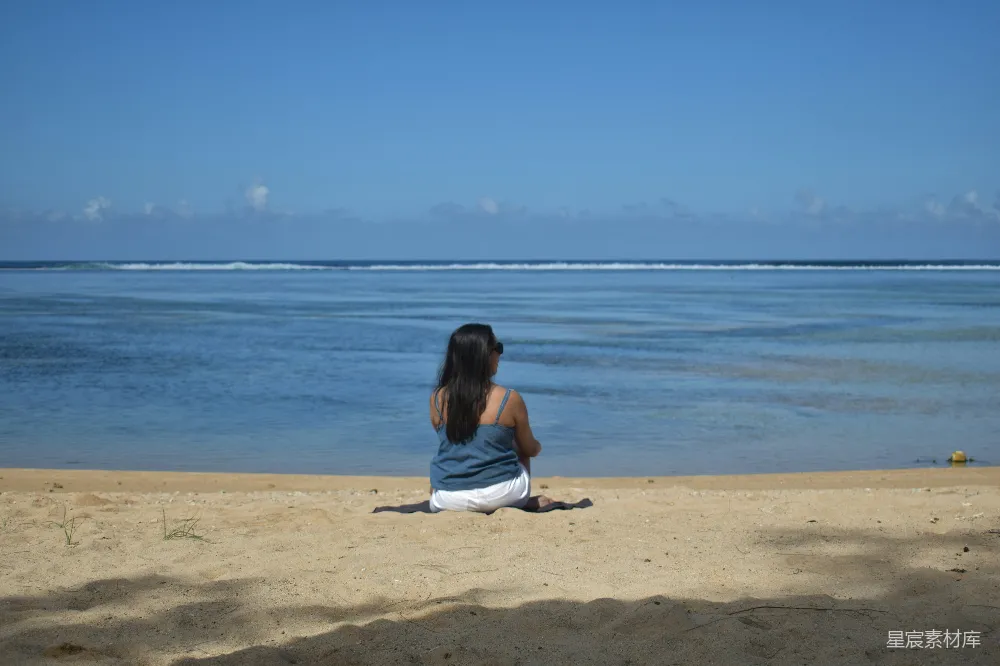 高清摄影 一个女人坐在海滩上，望着大海。