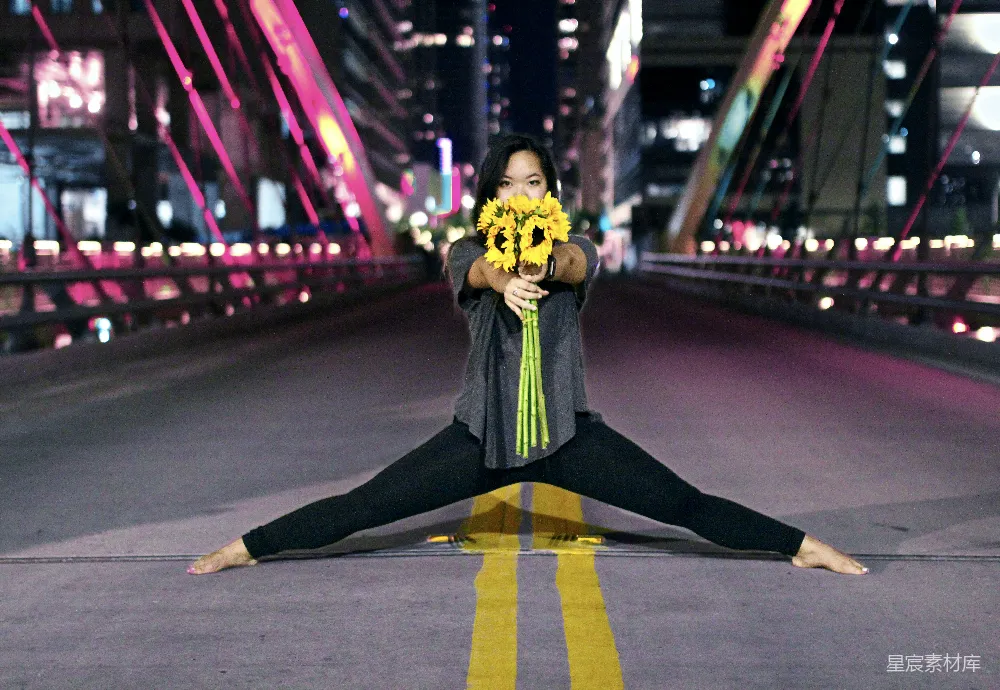 高清摄影 夜晚，一名妇女手持向日葵，在路中央将它们劈成两半。