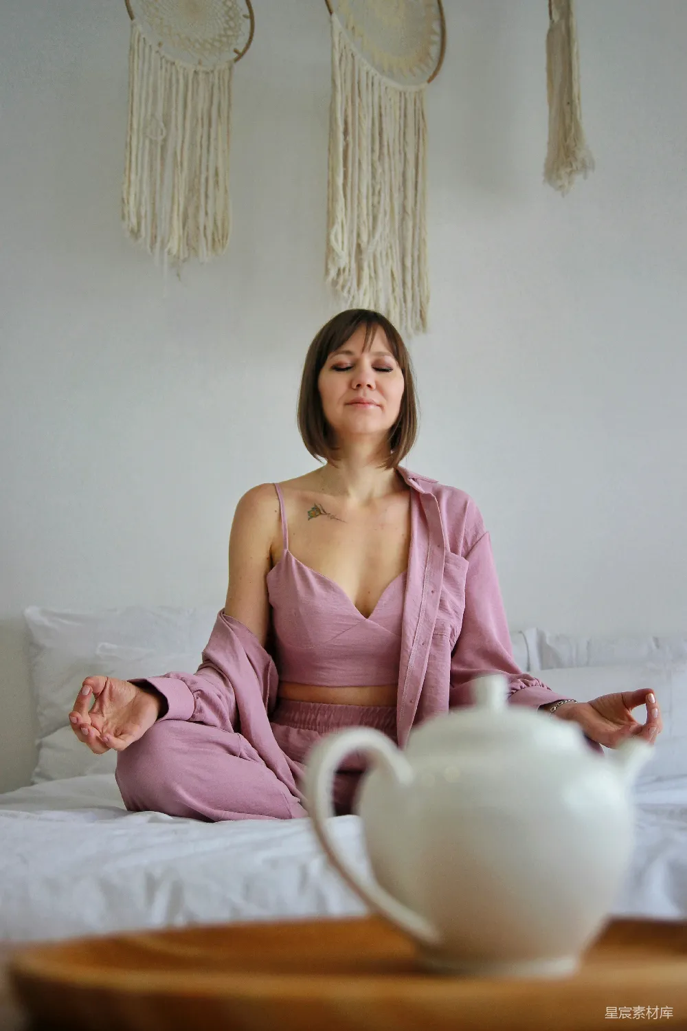 高清摄影 一个女人坐在床边，面前放着一个茶壶。