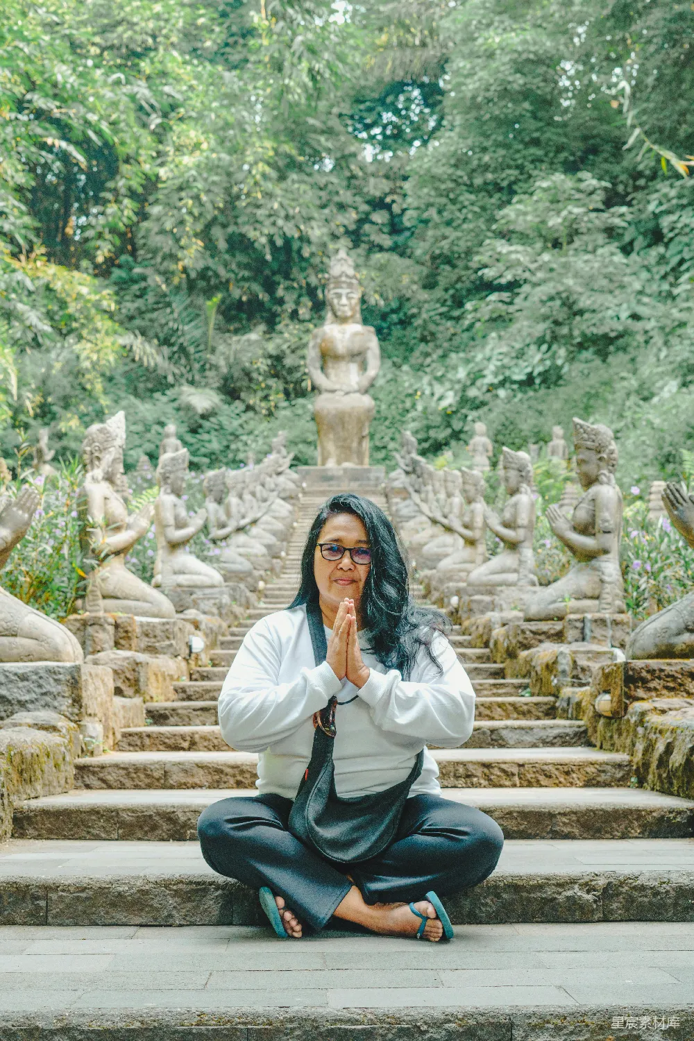 高清摄影 一个女人坐在一排佛像前地上