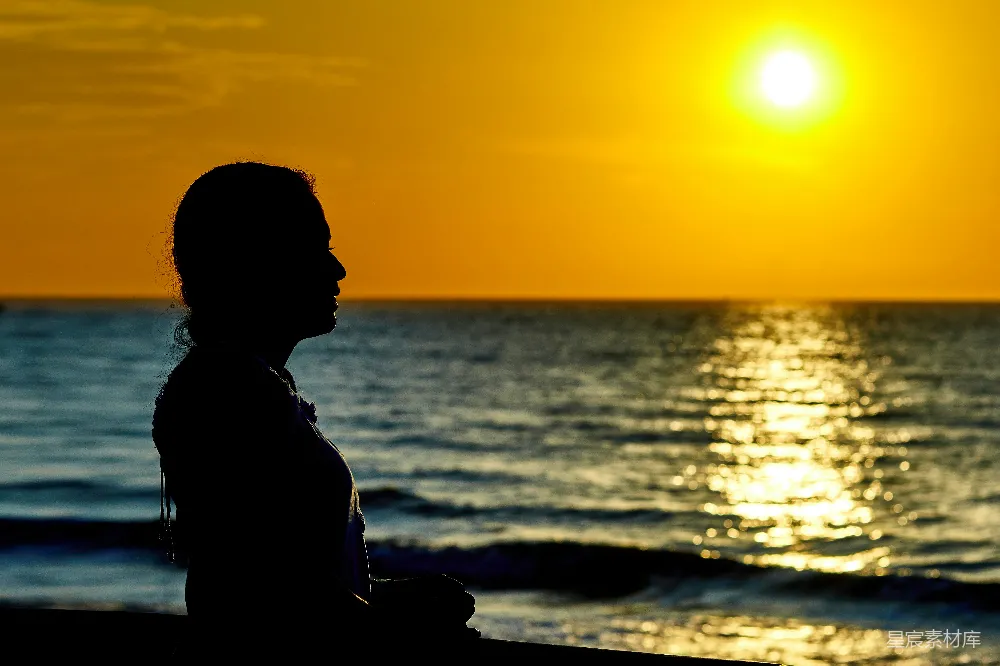 高清摄影 女人站在海滩上，夕阳西下。