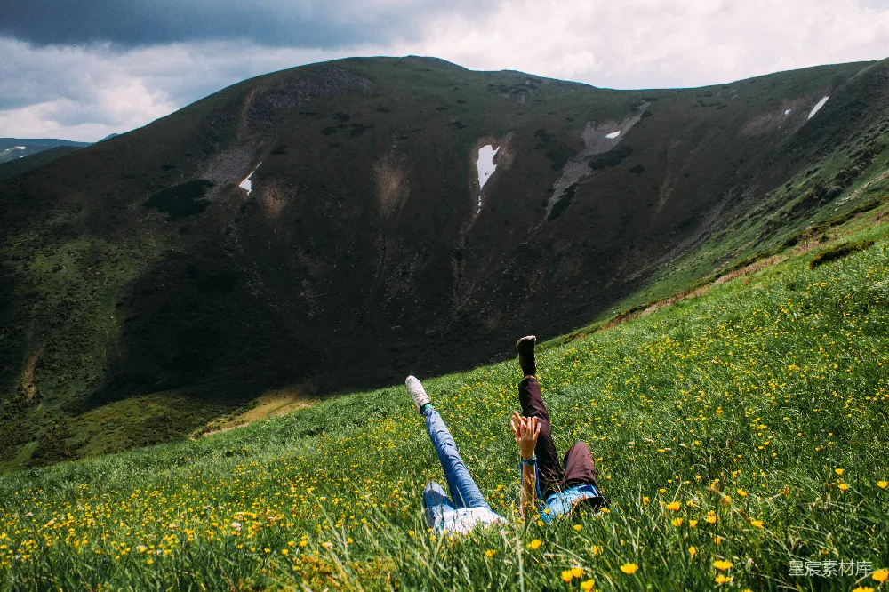 高清摄影  一个人在田野中躺着，背景是山。