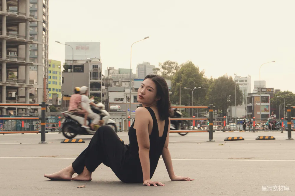 高清摄影 一个女人坐在地上，背景中有摩托车。