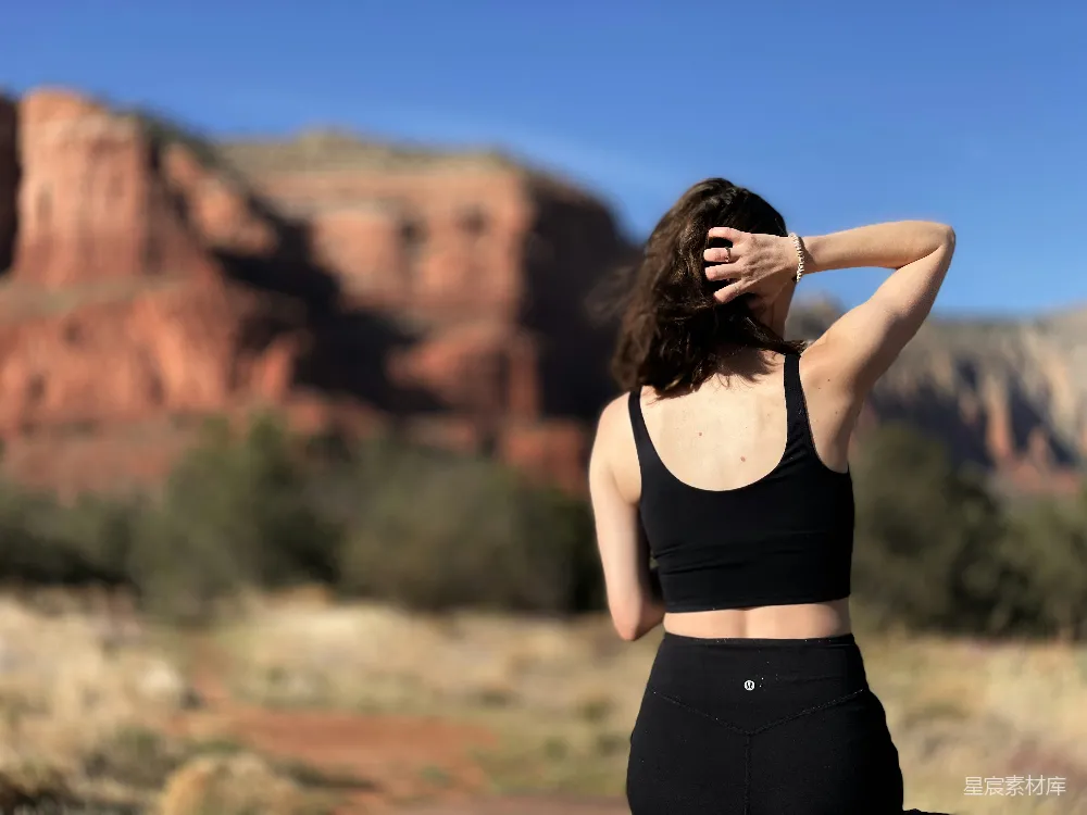 高清摄影  一个穿着黑色运动bra上衣和紧身 leggings 的女性站在前面。