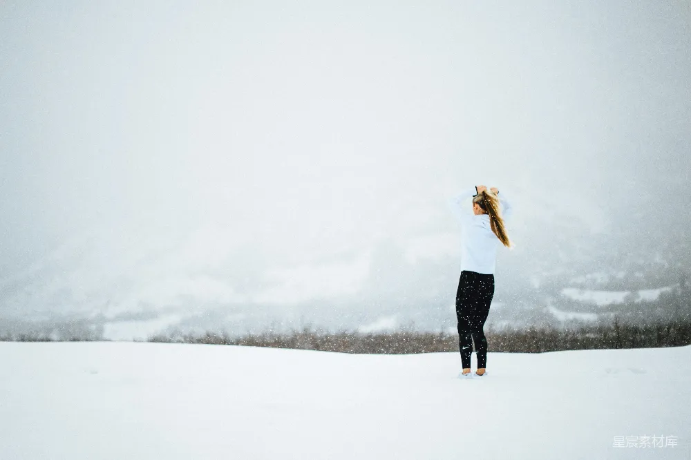 高清摄影 白天一名妇女站在覆盖着雪的空地上