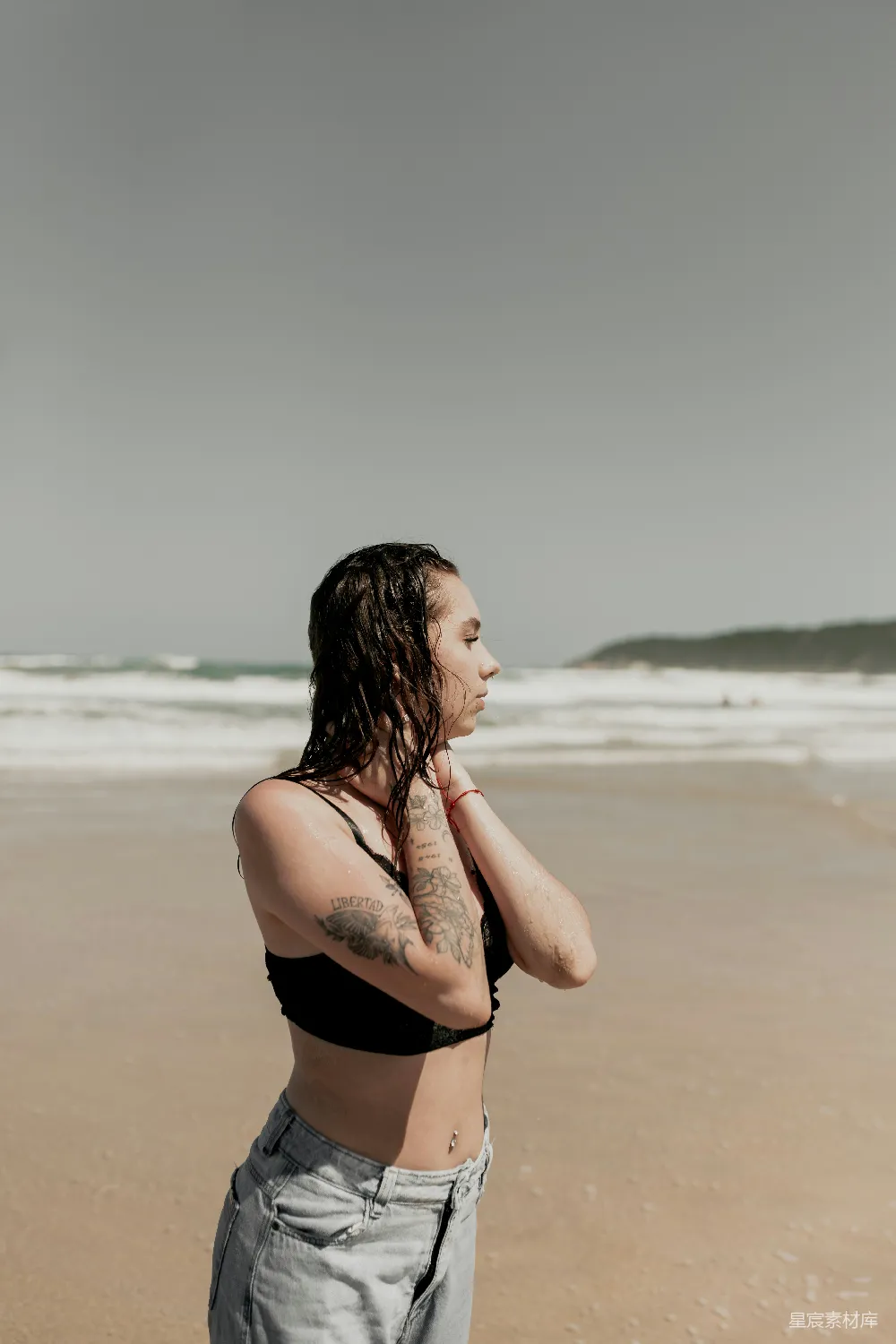 高清摄影 海滩上站着一位妇女，旁边是海洋。