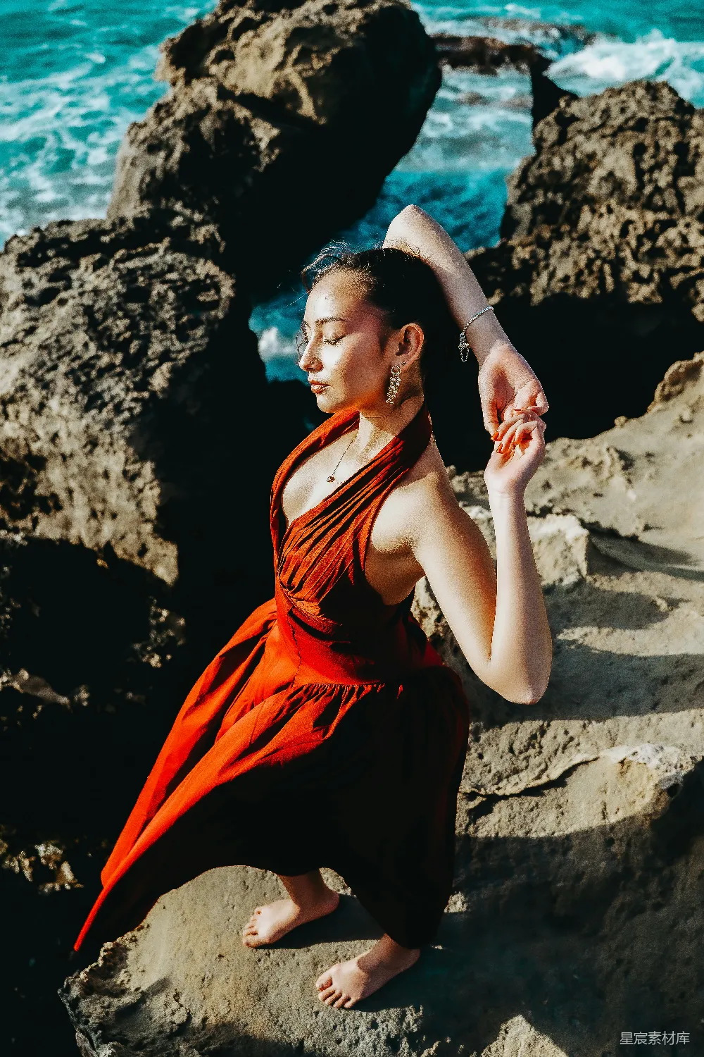 高清摄影 红衣女子站在海边岩石上摆姿势。