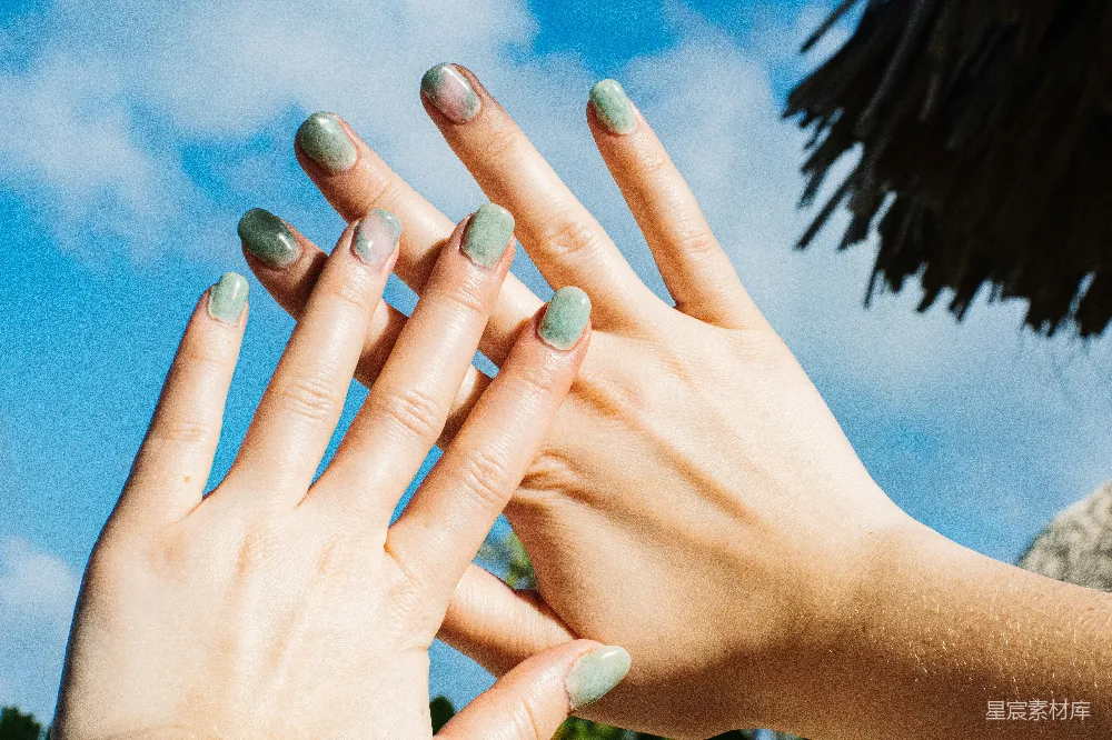 高清摄影 一个女子的手上涂着绿色的指甲油