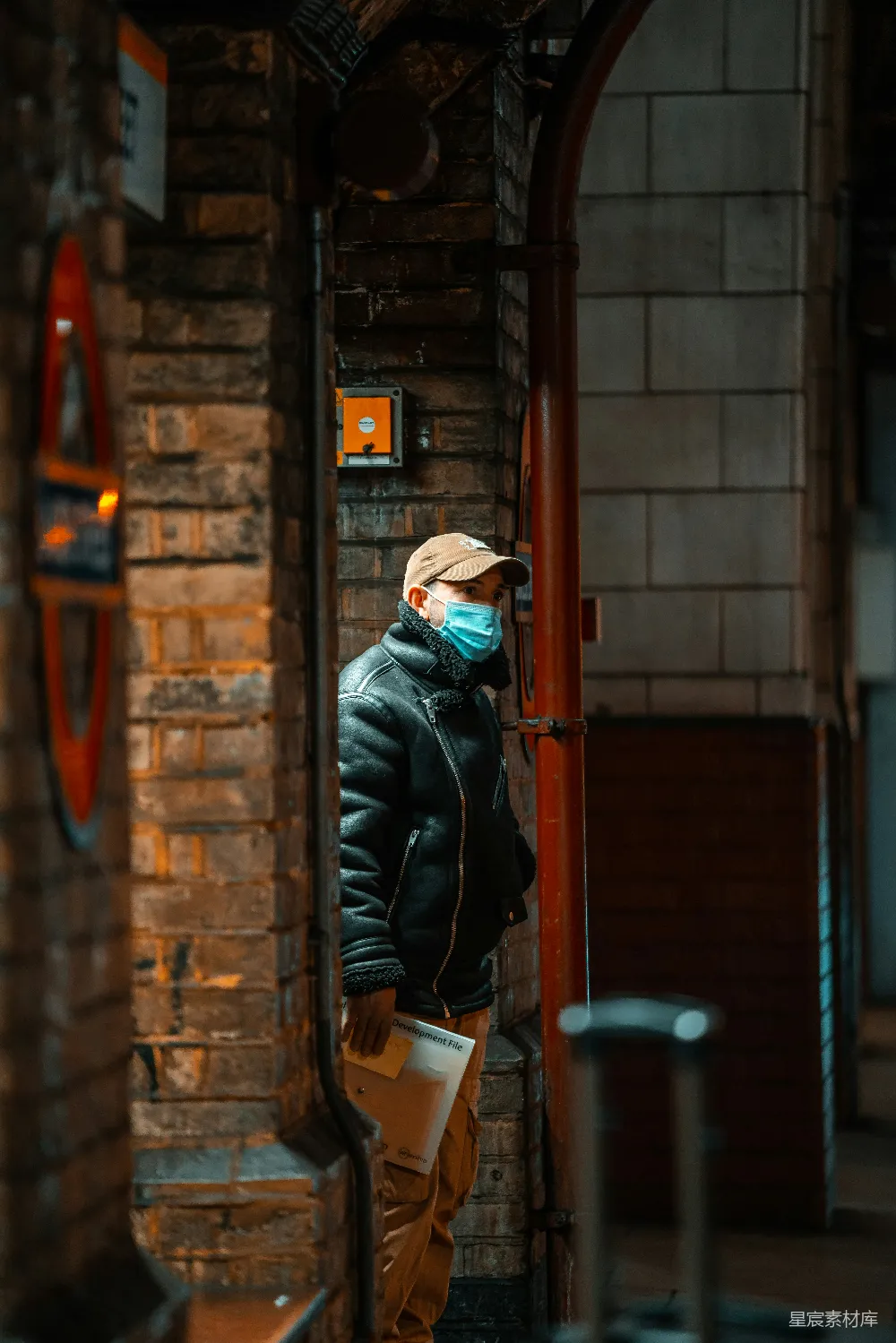 高清摄影 黑色夹克和棕色针织帽的男人站在一扇棕色木门前。