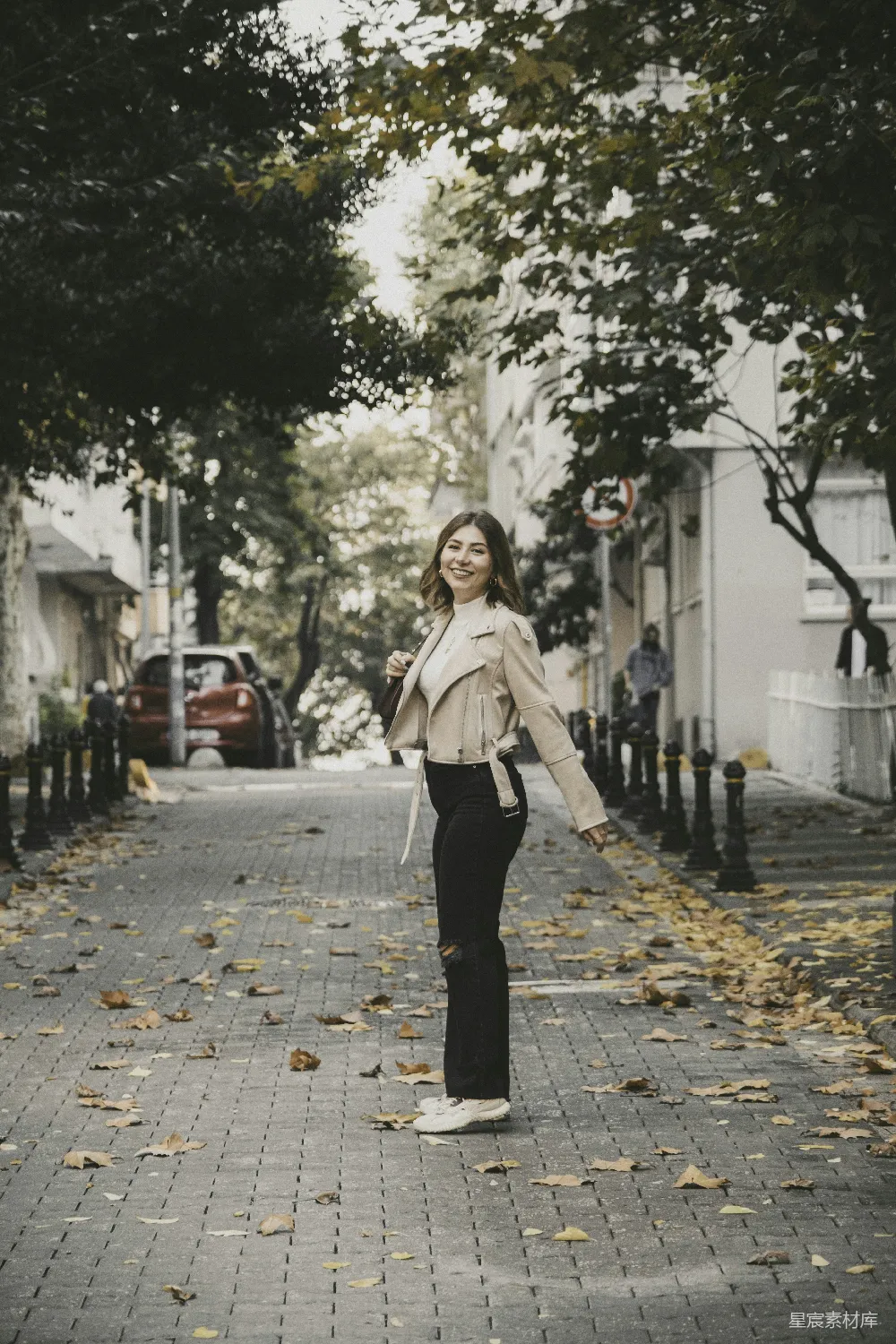 高清摄影 一个女人走在街道旁边，旁边是树木。
