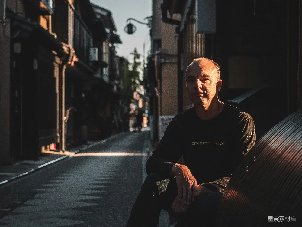 高清摄影 黑色外套的男人在 sidewalk 上白天坐着