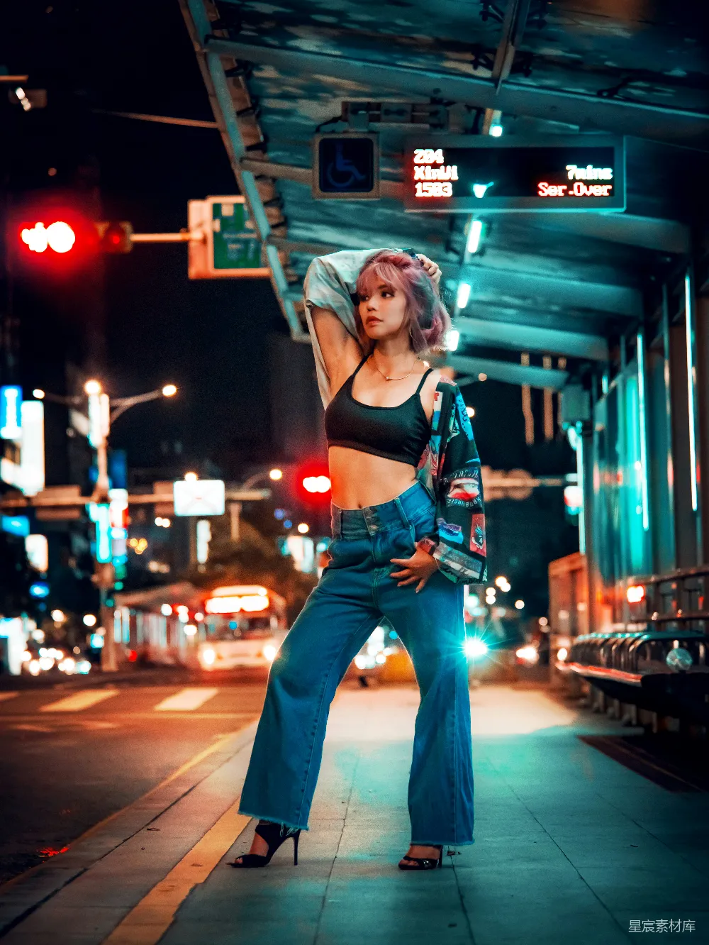 高清摄影 红背心和蓝色直筒牛仔裤的女人站在人行道上，夜间的景象。