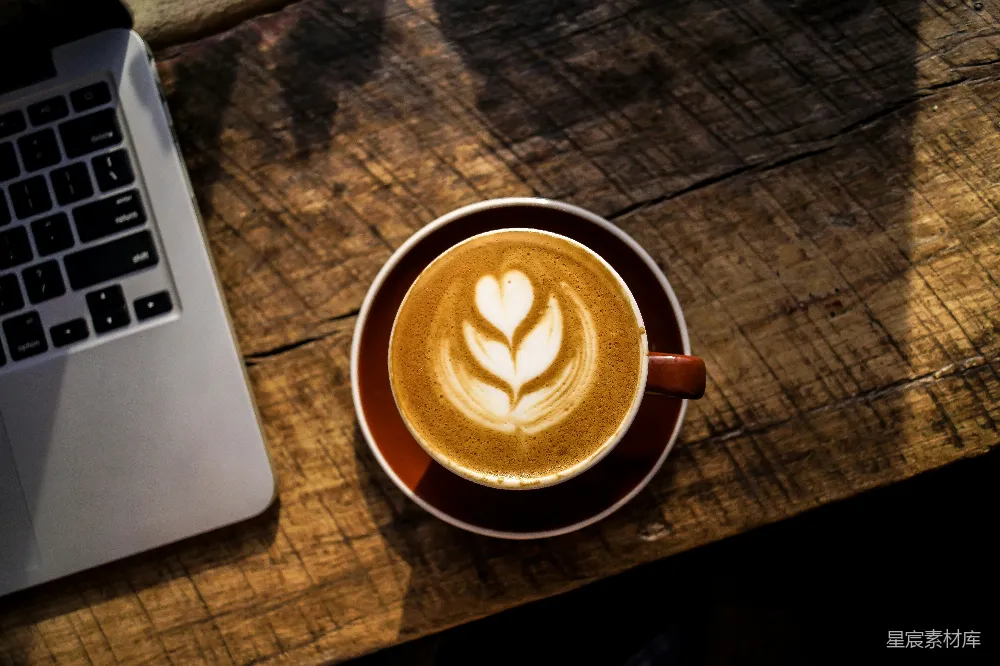 高清摄影 白瓷杯中caffè latte旁边是银色和黑色的笔记本电脑